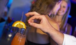 person putting a pill into a mixed drink